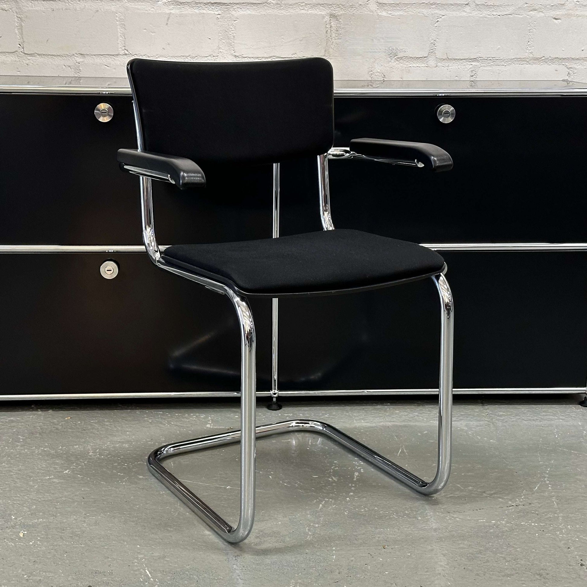 Black Thonet S43 PVF chair with chrome frame, wooden armrests, and fabric upholstery.