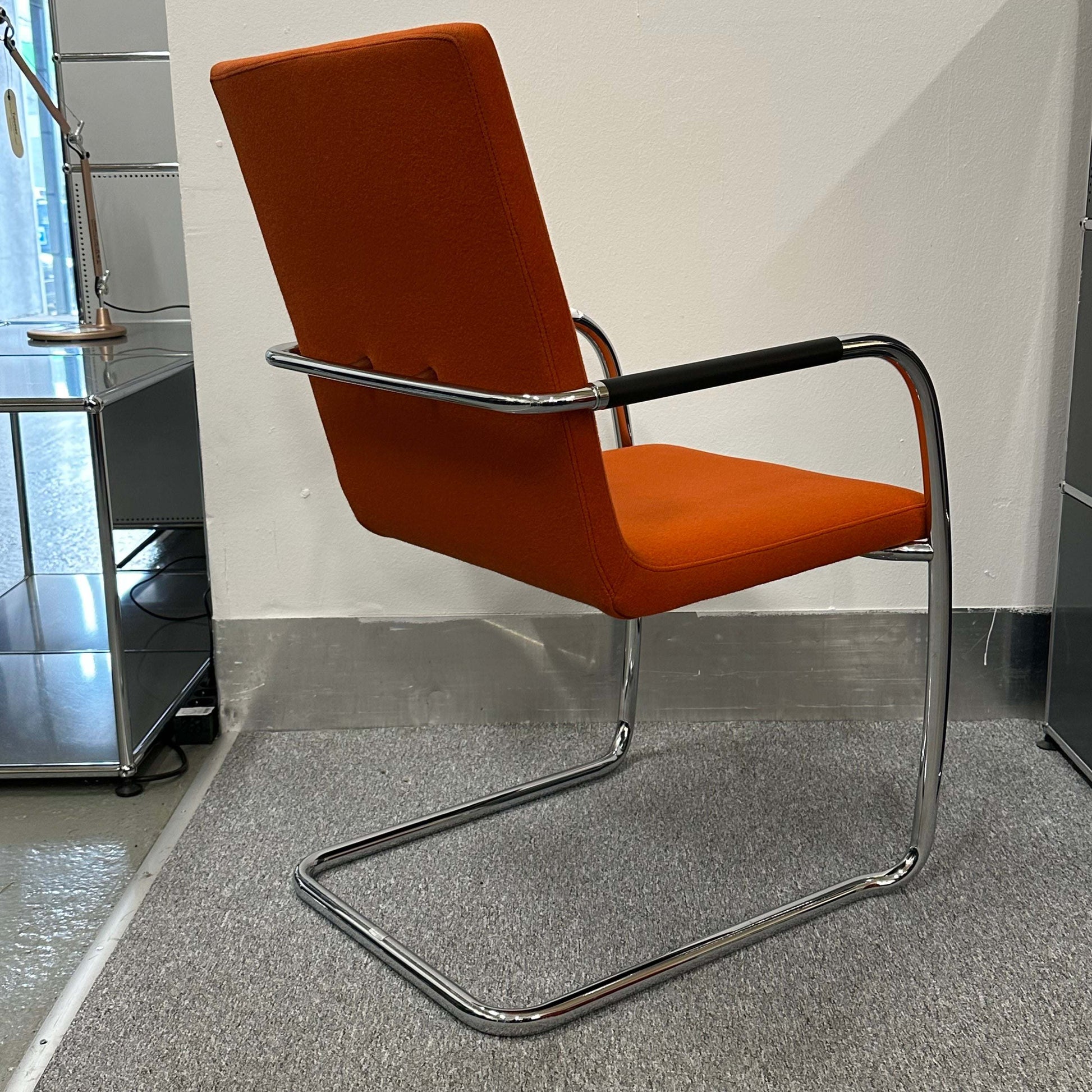 Thonet S60 chair with chrome frame and deep orange fabric seat and backrest, stackable design