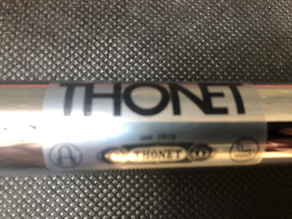 Close-up of chrome frame with Thonet logo on textured surface for Thonet S60 chair