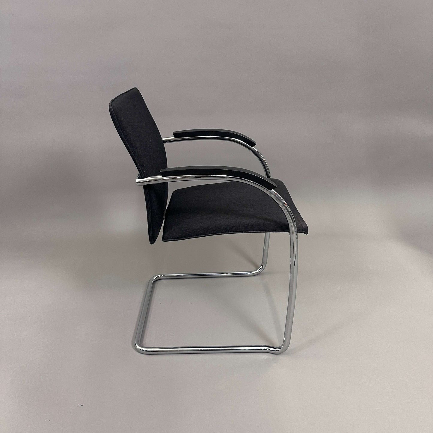 Thonet S78/S79 Freischwinger chair with black upholstery, matte black wooden armrests, and chrome frame viewed from side