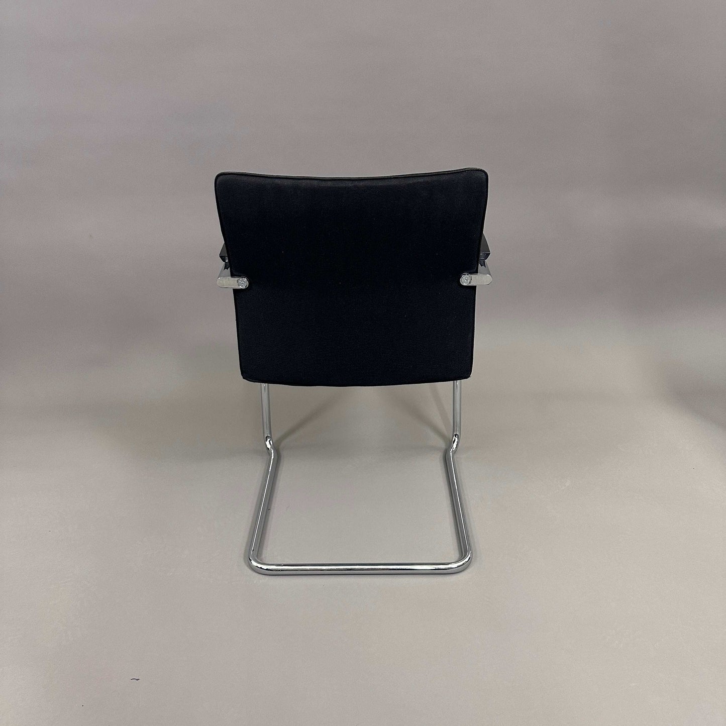 Thonet S78/S79 cantilever chair with black upholstery, matte black wooden armrests, and chrome frame viewed from the back