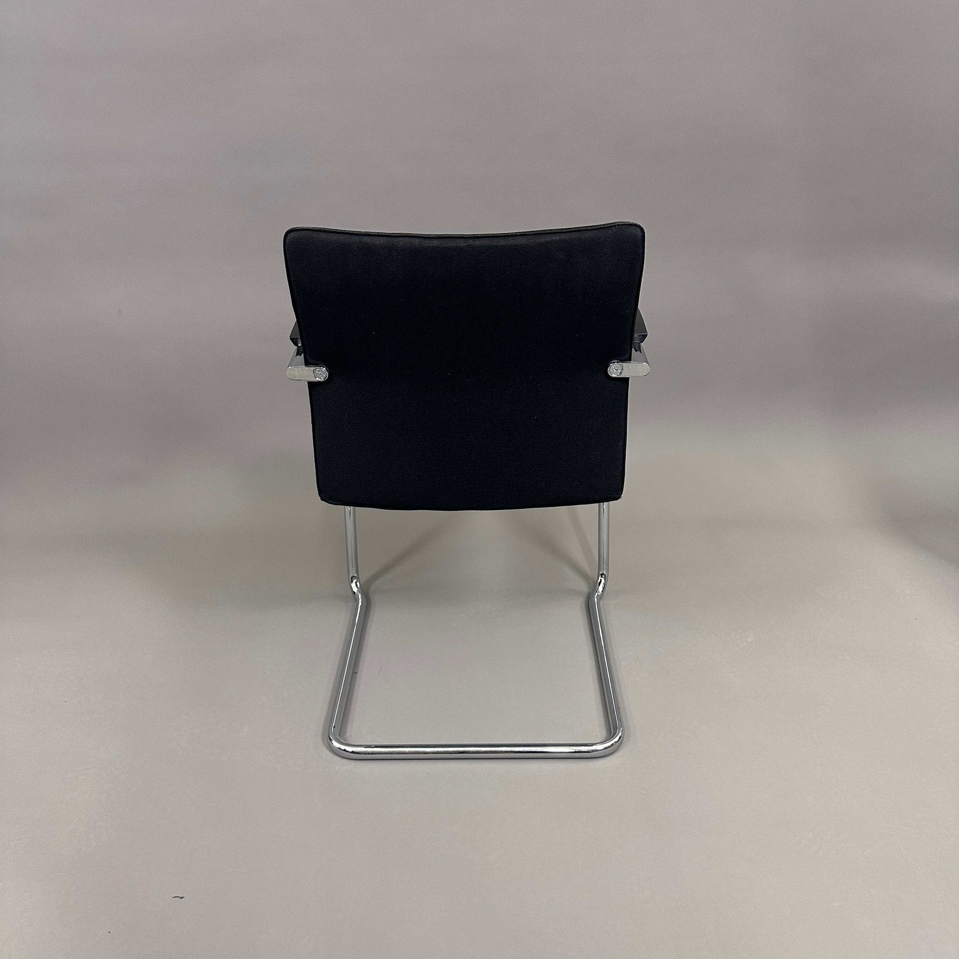 Thonet S78/S79 cantilever chair with black upholstery, matte black wooden armrests, and chrome frame viewed from the back