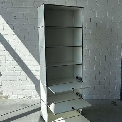 USM Haller 1x6 Highboard weiß mit 3 Klappen und offenem Regal vor weißer Ziegelwand