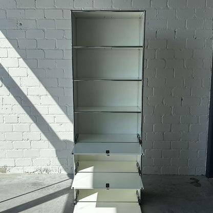 USM Haller 1x6 Highboard weiß mit 3 Klappen vor weißer Backsteinwand und Lichteinfall