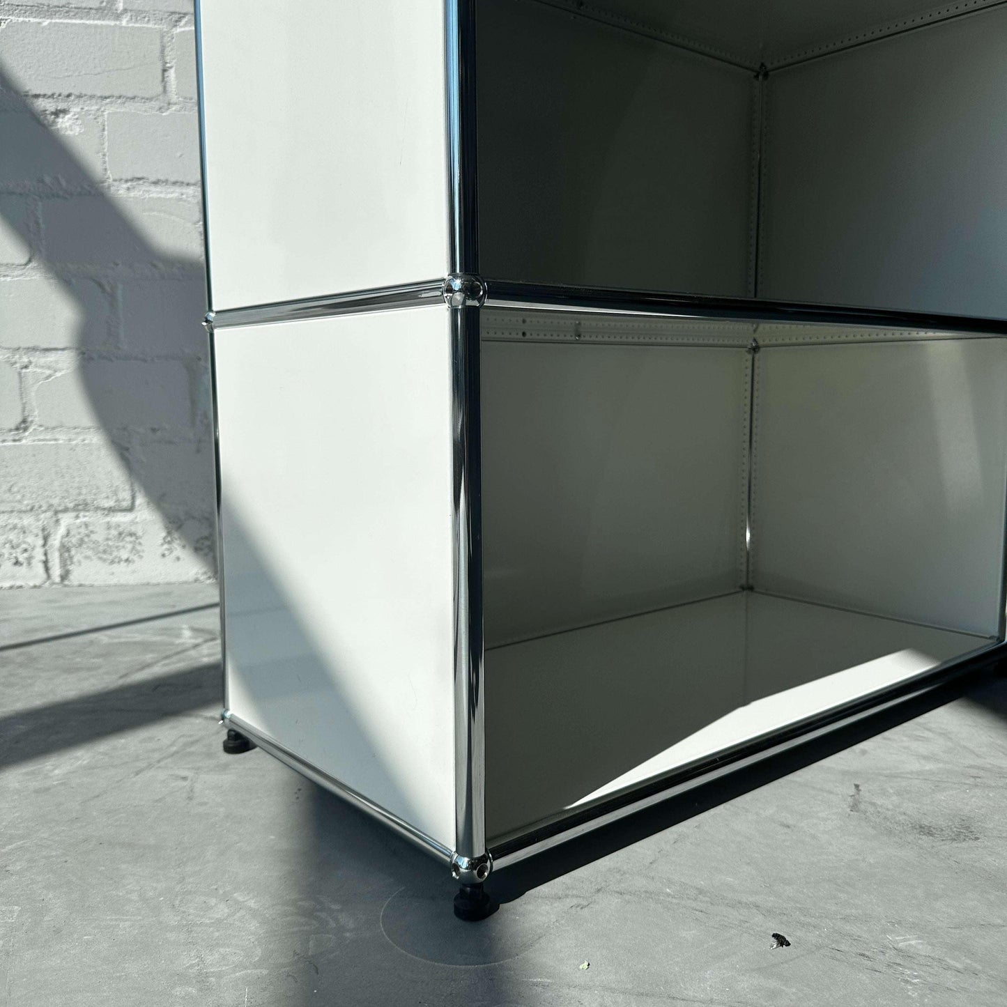 USM Haller 1x6 weißes offenes Highboard aus Metall mit verchromten Details auf grauem Boden