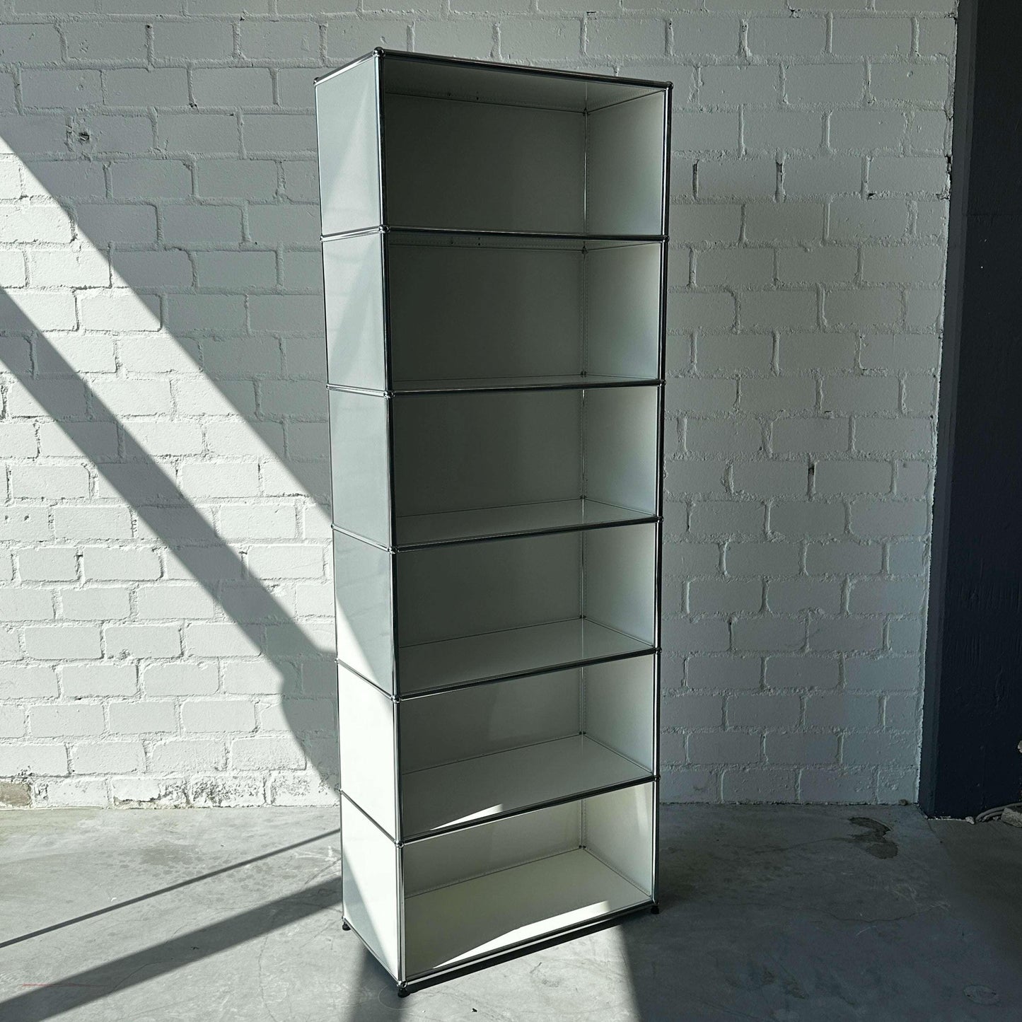 USM Haller 1x6 Highboard weiß offen mit sechs Fächern vor weißer Backsteinwand