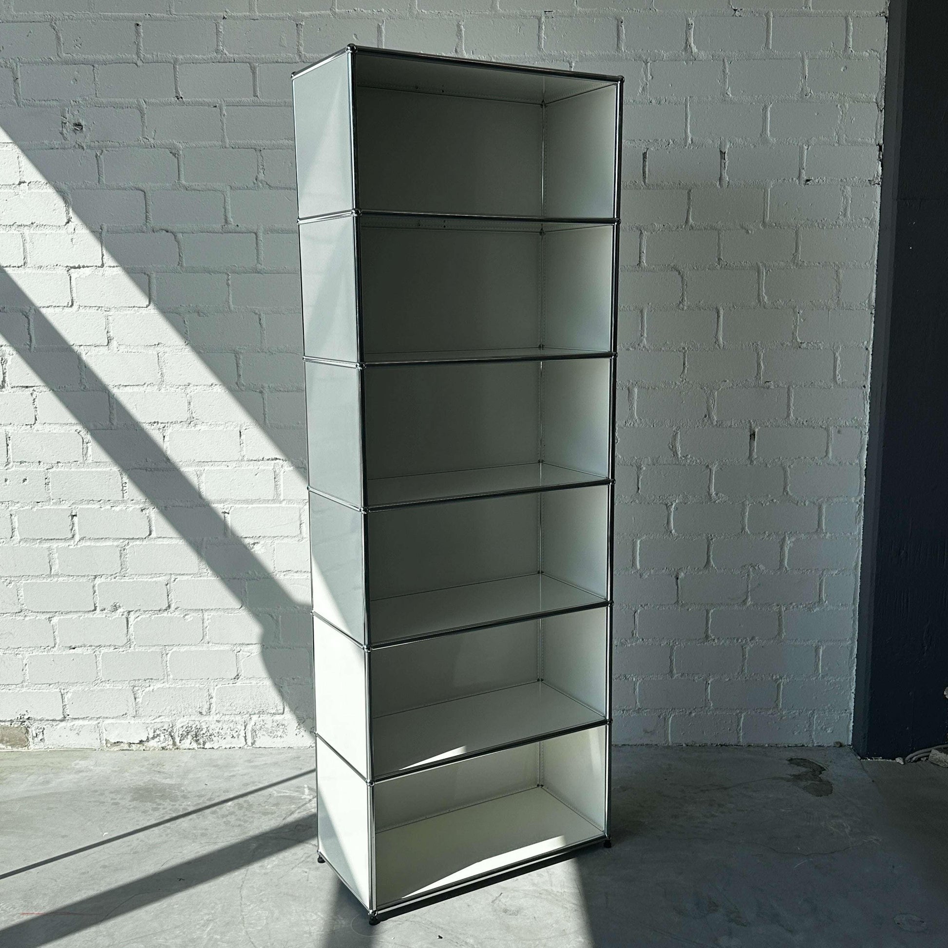 USM Haller 1x6 Highboard weiß offen mit sechs Fächern vor weißer Backsteinwand