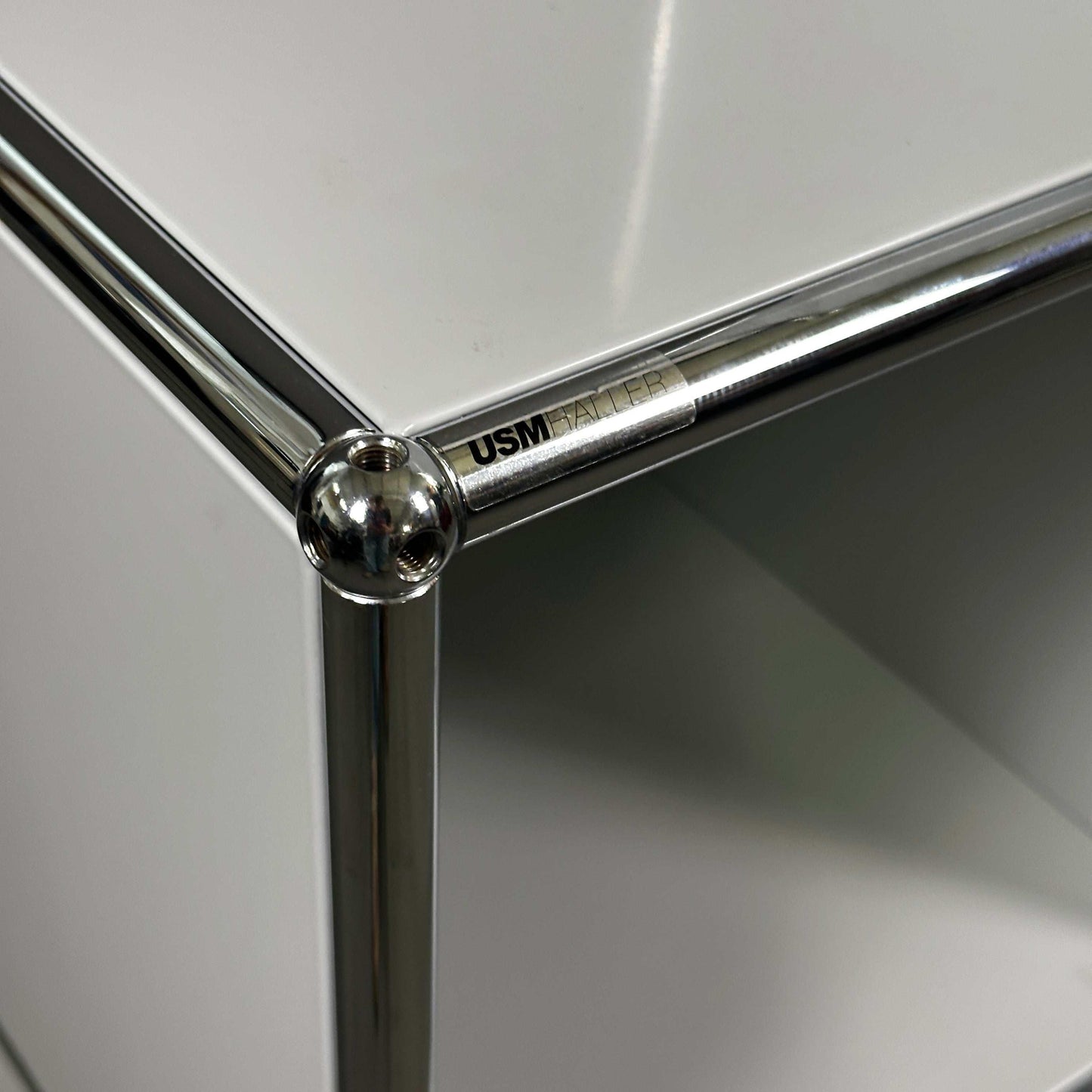 Detailaufnahme USM Haller Highboard lichtgrau mit chrom Rahmen und klarer Markenkennzeichnung