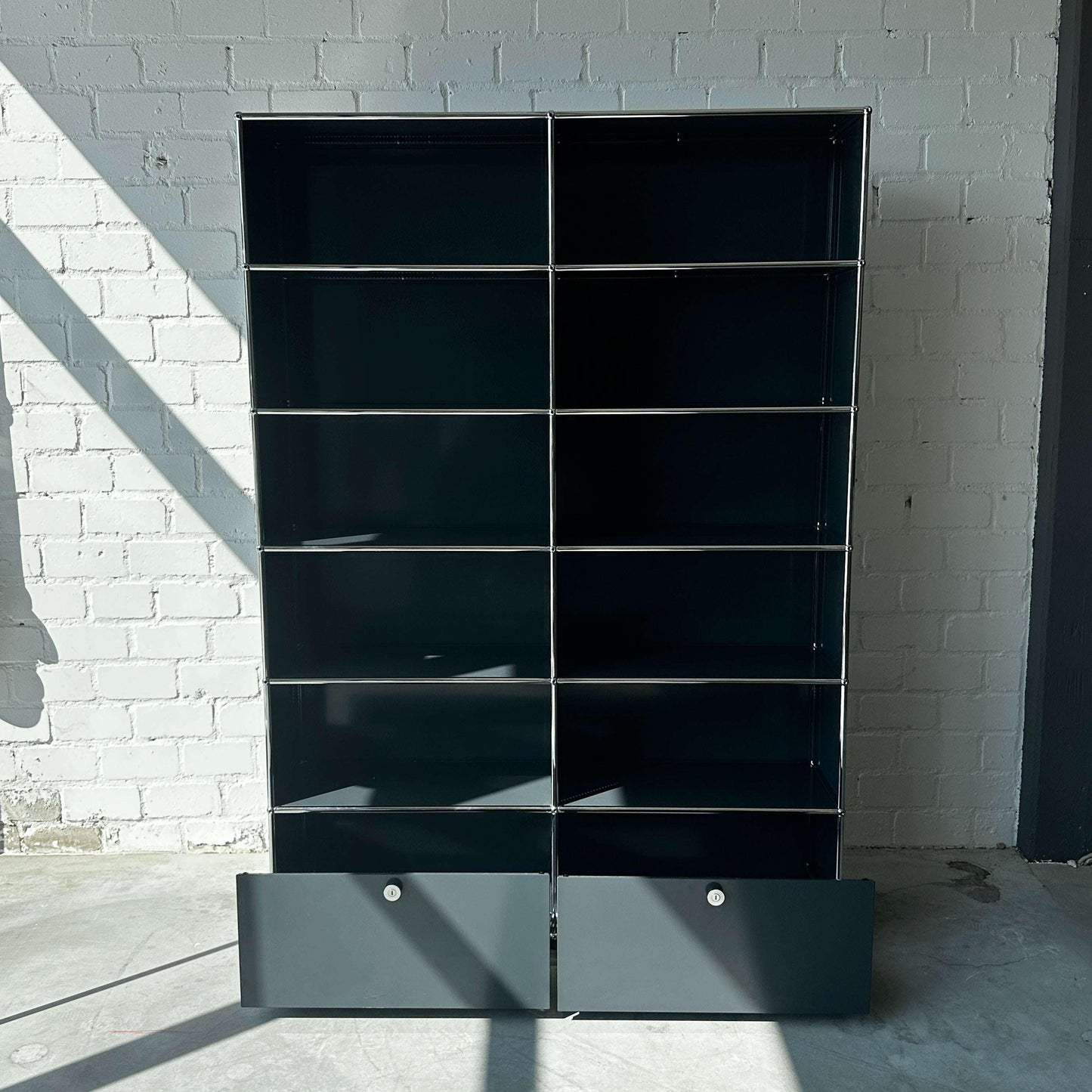 USM Haller anthrazitgraues 2x6 Highboard mit zwei Schubladen vor weißer Backsteinwand