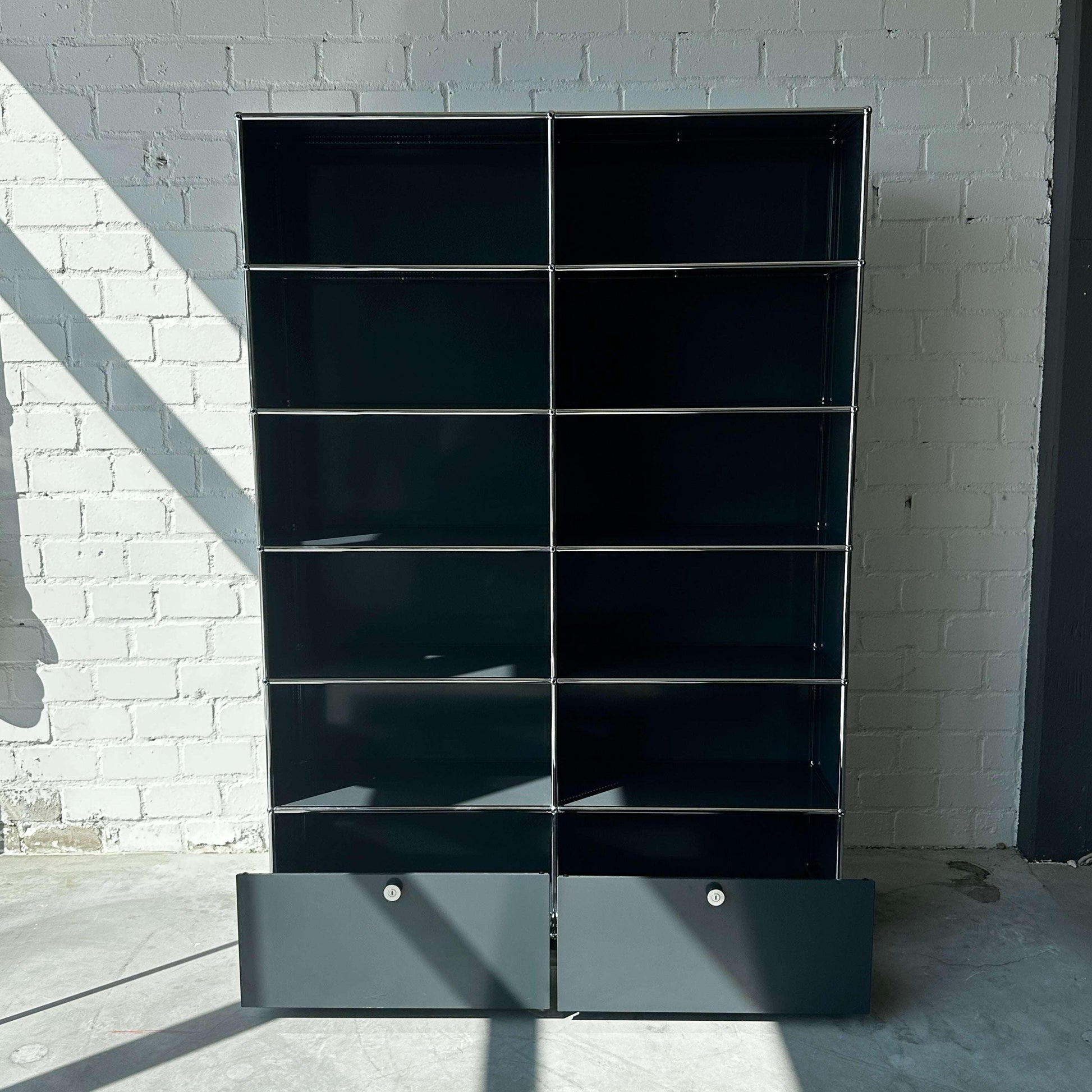 USM Haller anthrazitgraues 2x6 Highboard mit zwei Schubladen vor weißer Backsteinwand