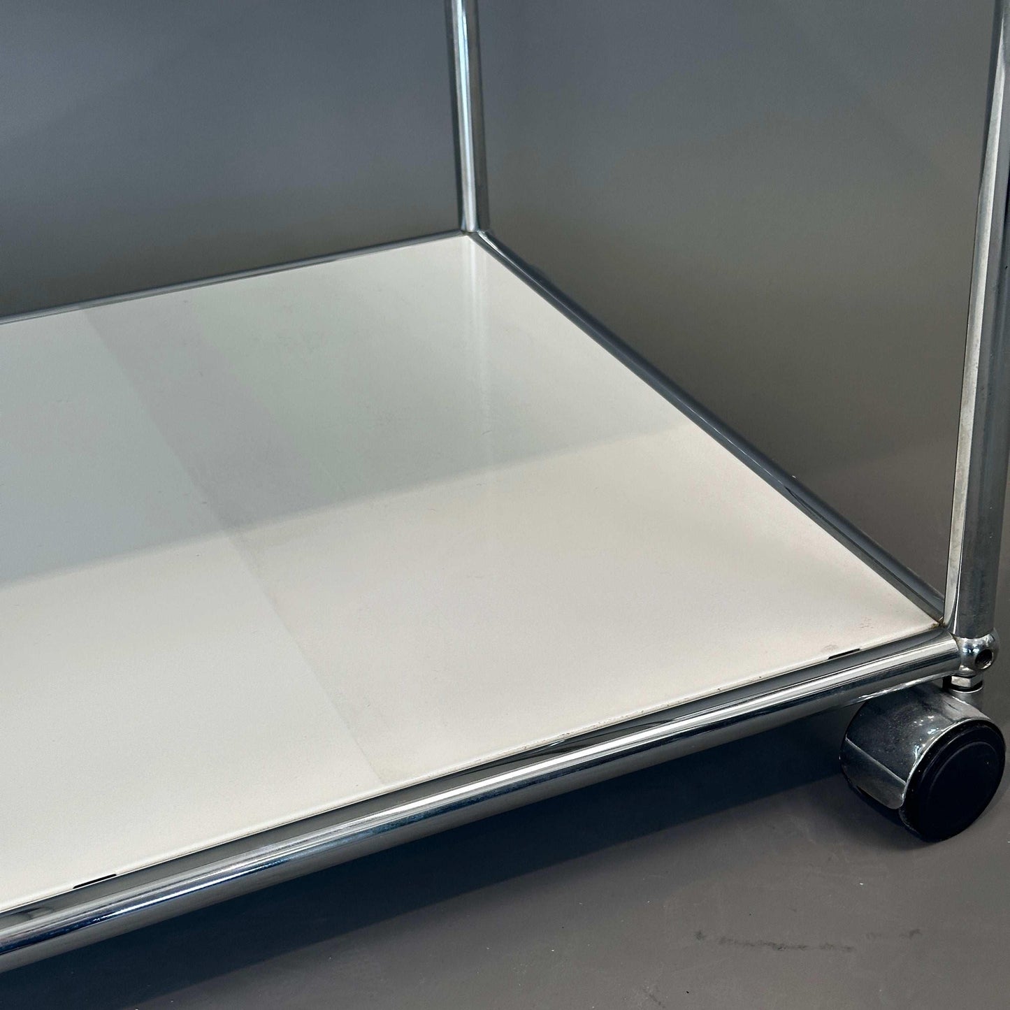 USM Haller weißer Beistelltisch mit Rollen, 50 cm tief, close-up der Ablagefläche und Laufrolle