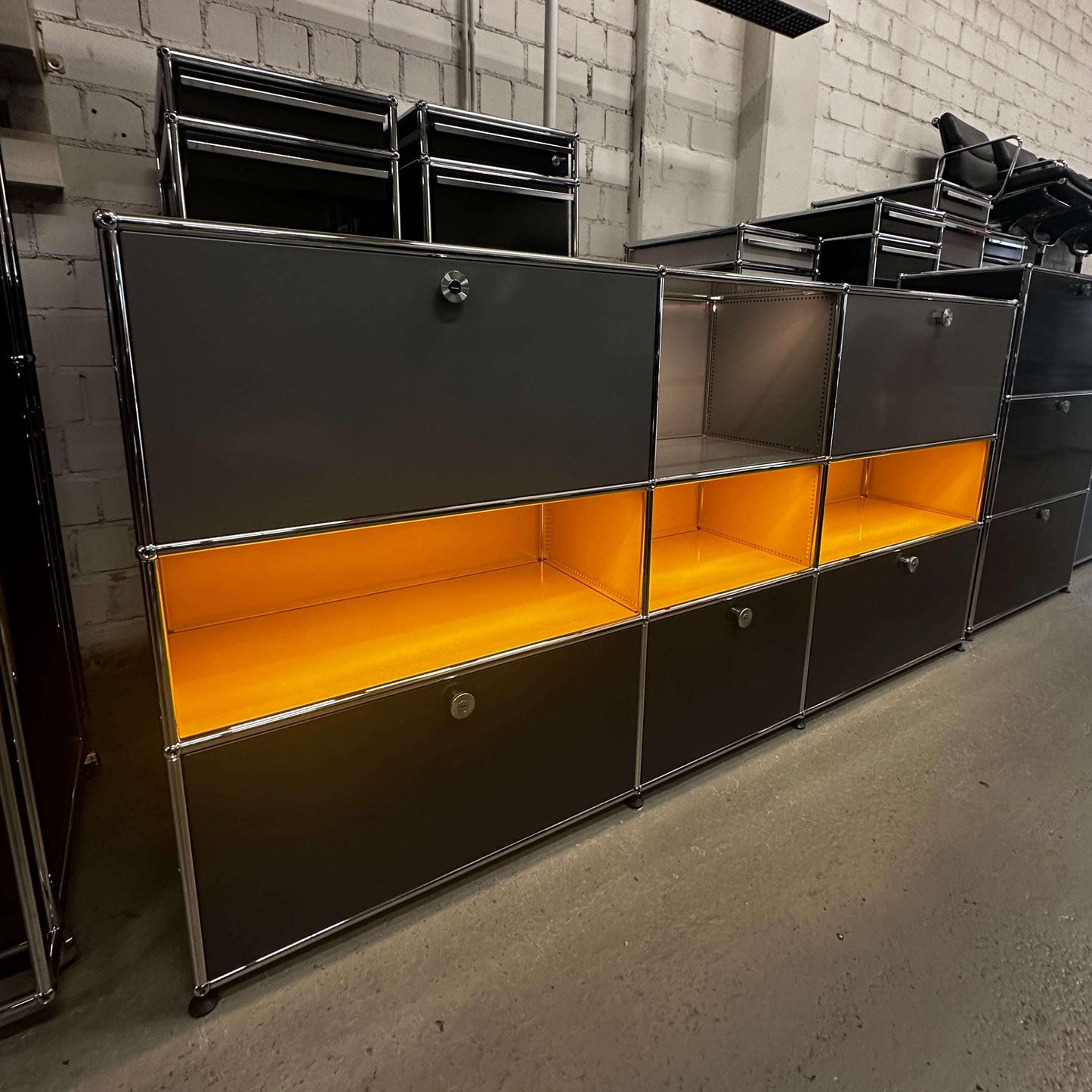 USM Haller E Highboard anthrazitgrau mit goldgelben beleuchteten Fächern und integriertem Stromsystem