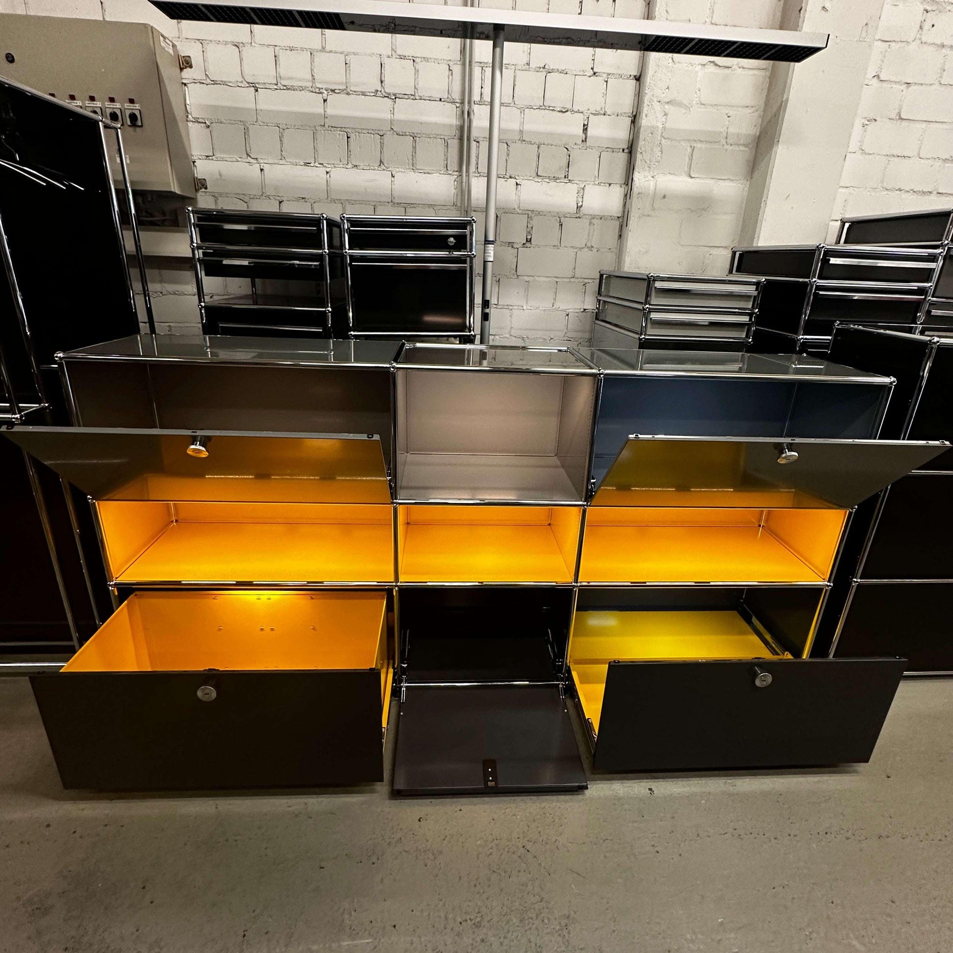 USM Haller E Highboard anthrazitgrau mit goldgelben beleuchteten Fächern in modernem Design