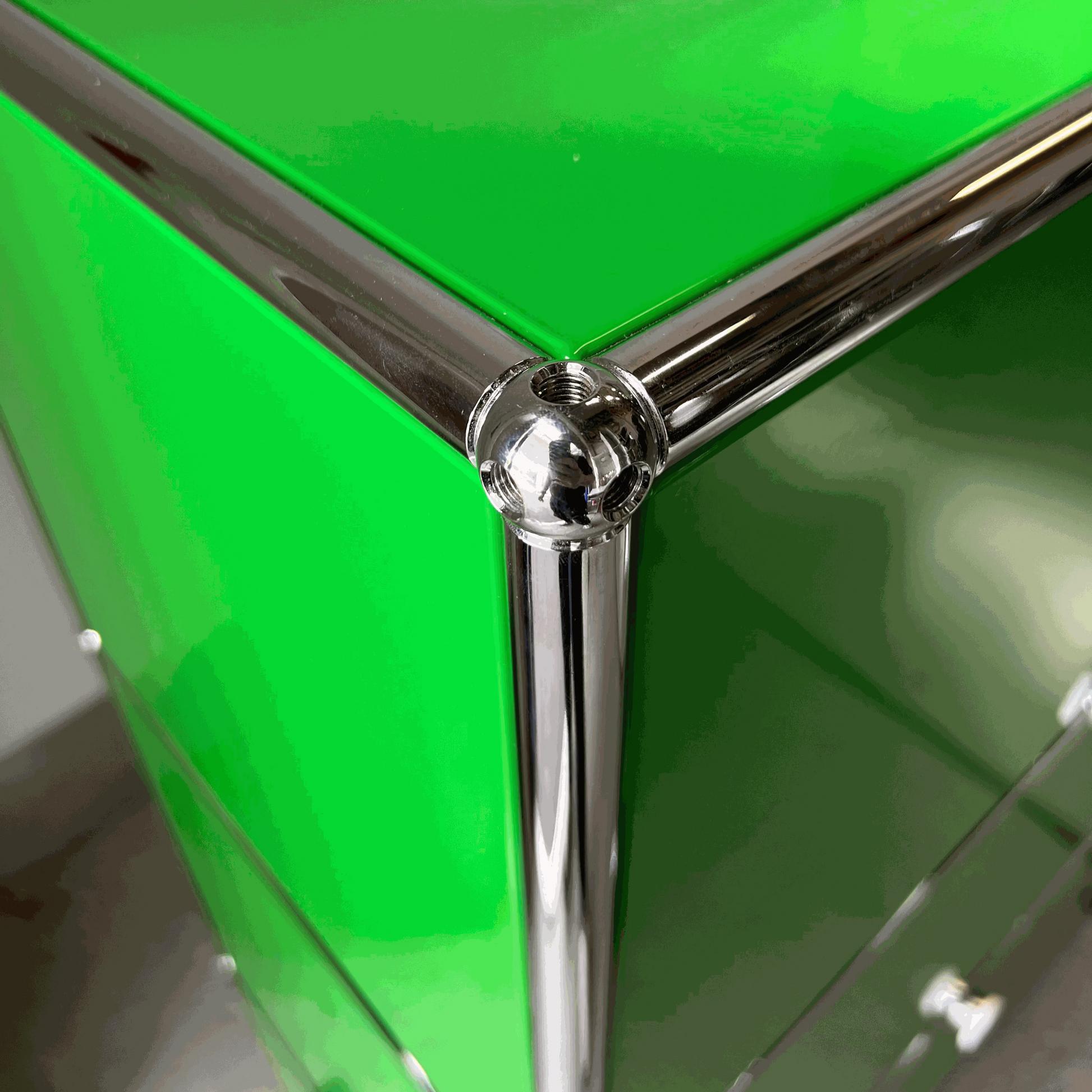 Close-up of green USM Haller Highboard corner with chrome metal frame and screws