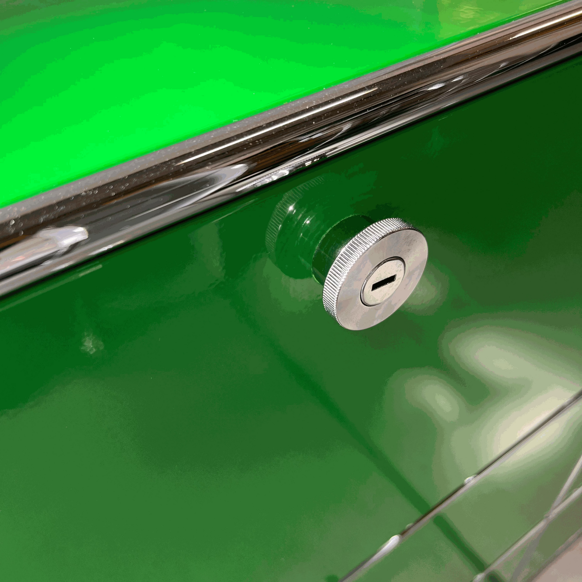 Close-up of a green USM Haller Highboard with chrome lock and soft-close flap detail
