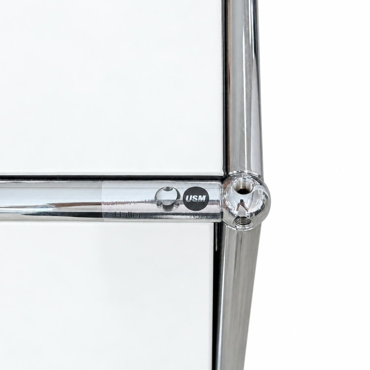 Detailansicht eines USM Haller Highboards in Reinweiß mit verchromtem Stahlrohrrahmen und charakteristischem Kugelgelenk.