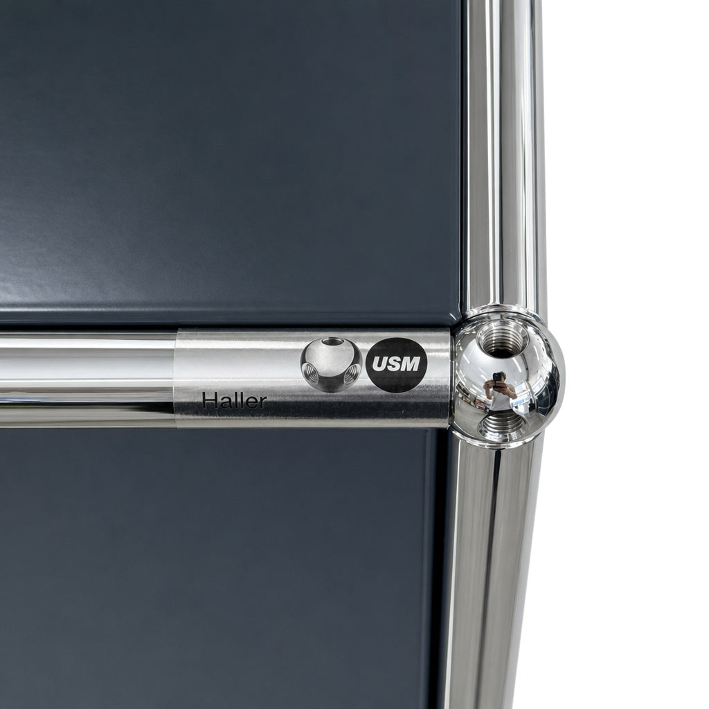 USM Haller Highboard in Anthrazit mit charakteristischer verchromter Rohrstruktur und markantem Kugelverbindungselement.