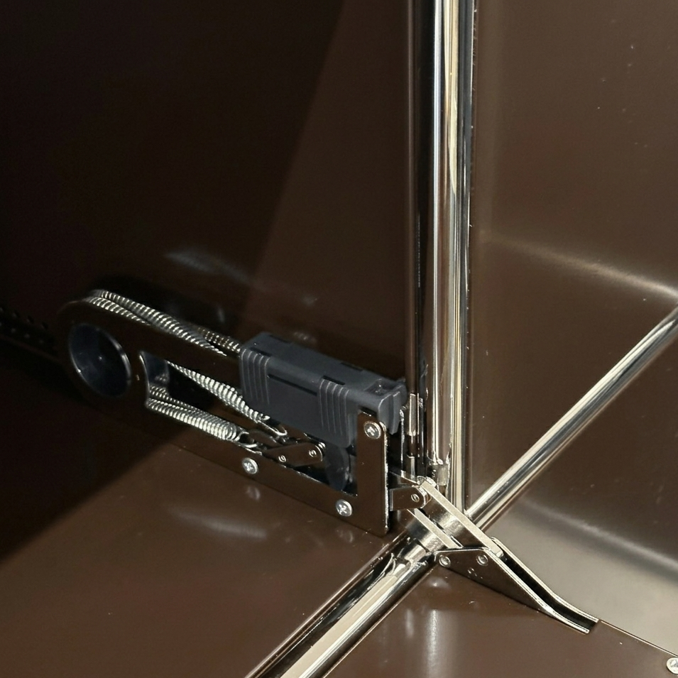 USM Haller Highboard Detail: braunes Metallmodul mit verchromtem Gestell und Klappenmechanismus.