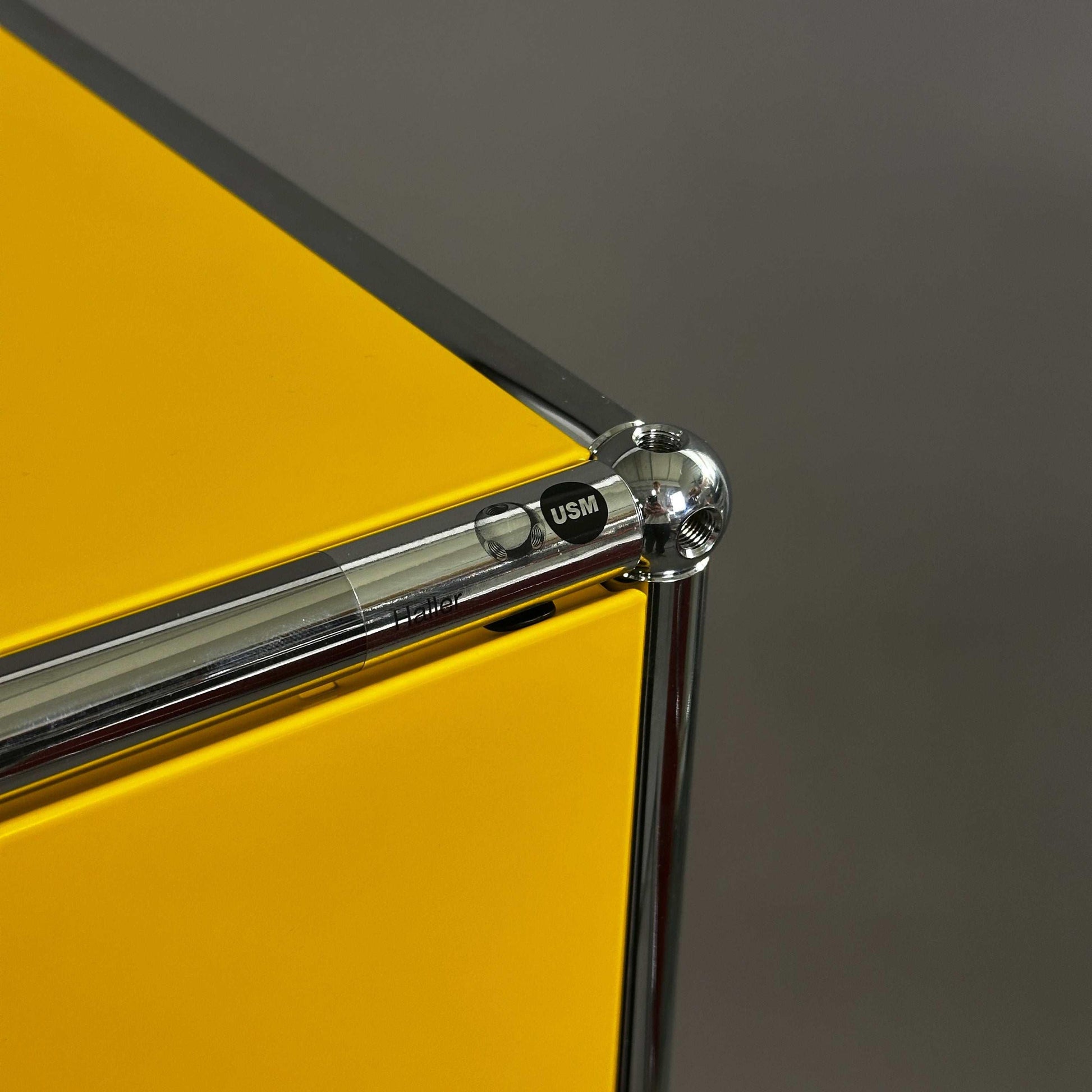 USM Haller Highboard 1x3 gelb mit Klappen und verchromtem Gestell in Nahaufnahme