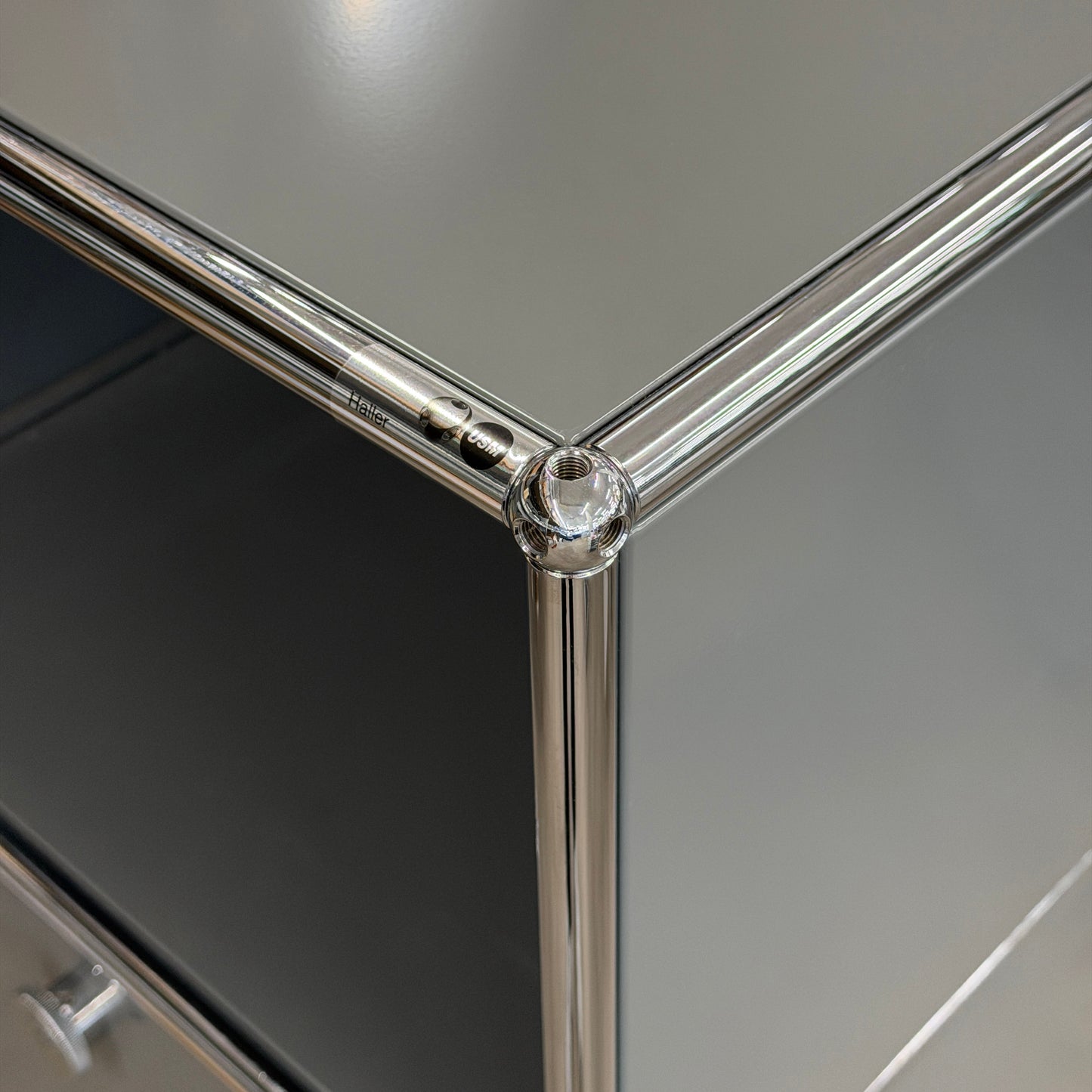 USM Haller Highboard 1x3 in mittelgrau mit verchromten Stahlrohren und zwei Klappen.