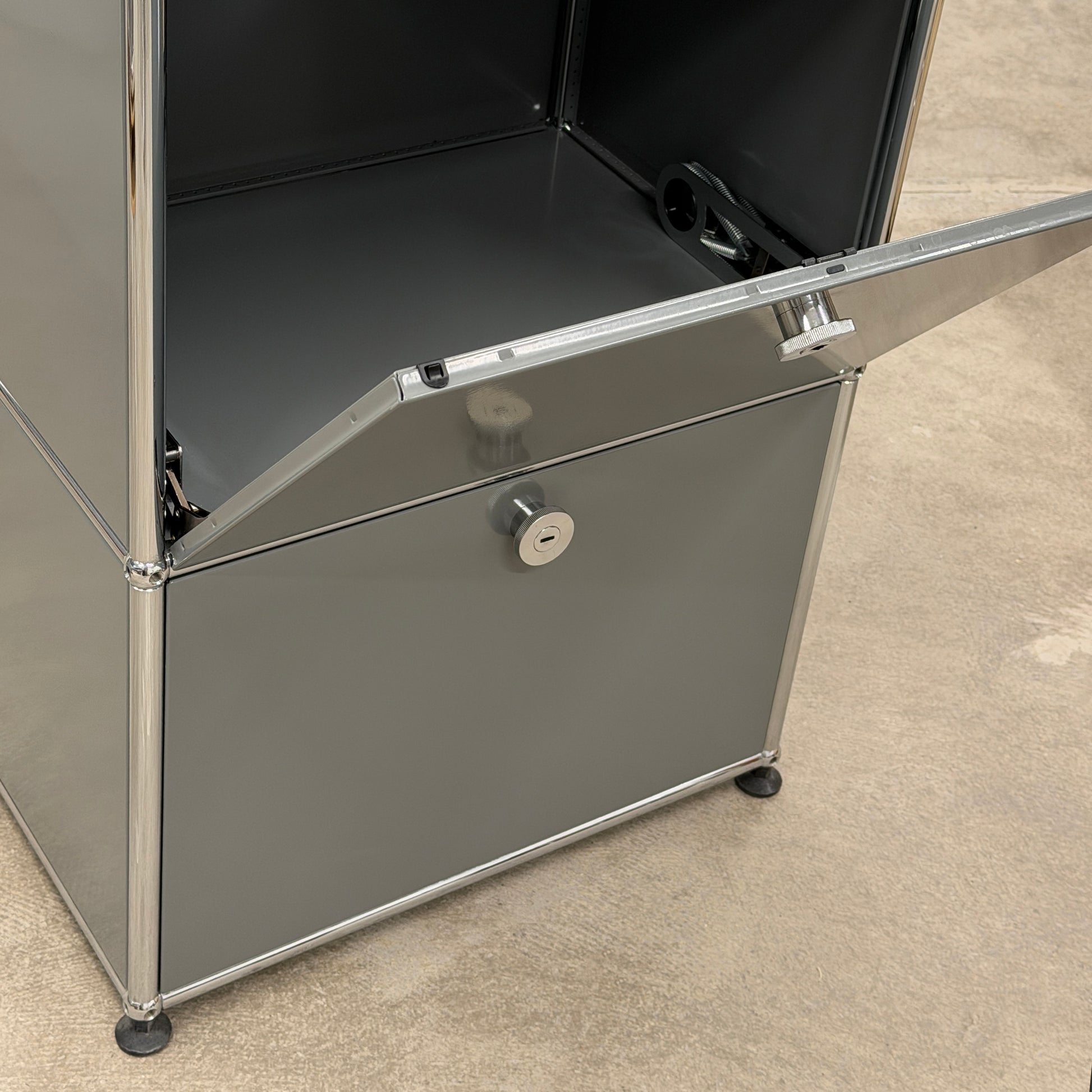 USM Haller Highboard 1x3 in mittelgrau mit zwei offenen Klappen und Chromgestell.