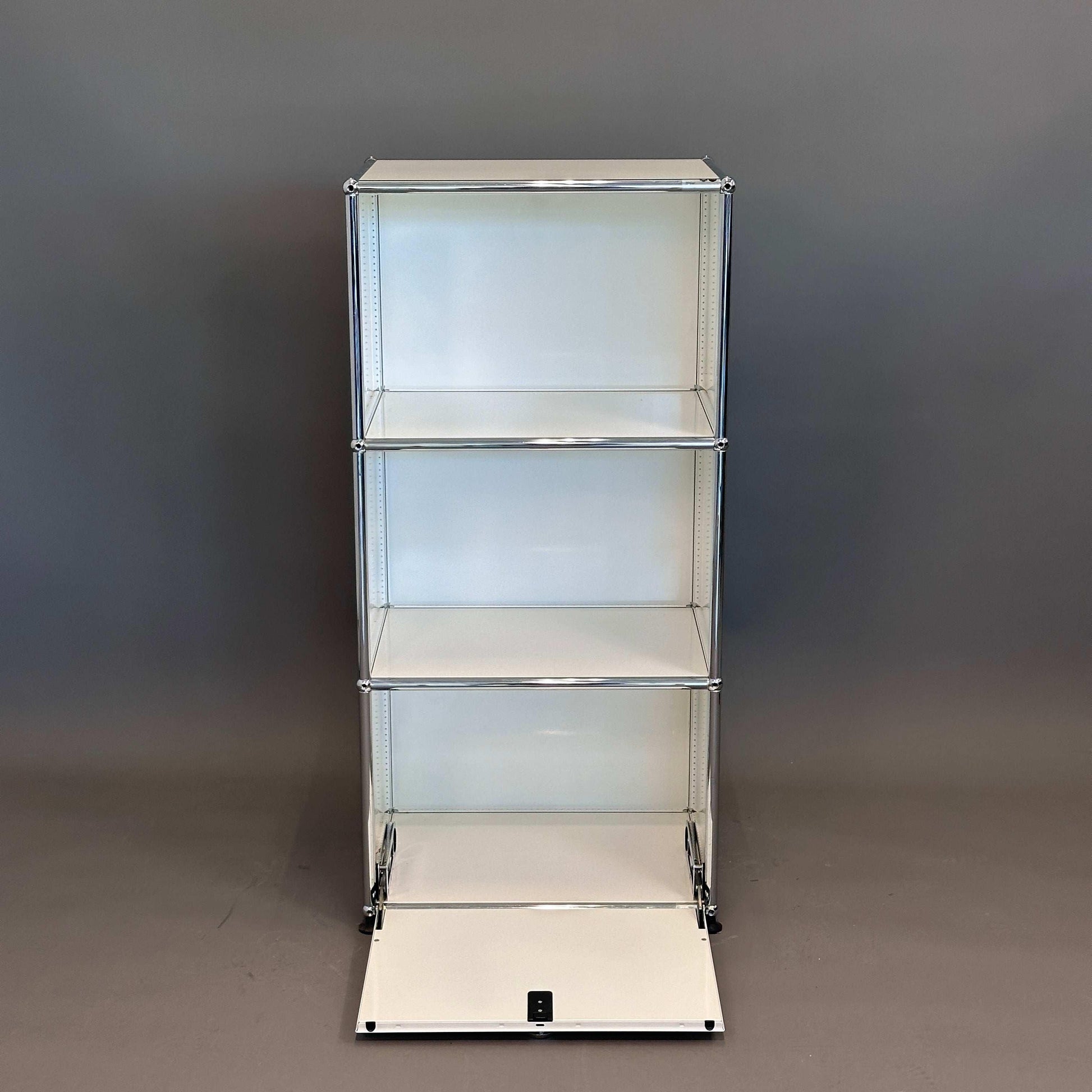 USM Haller Highboard 1x3 weiß mit geöffneter Klappe und drei Einlegeböden vor grauem Hintergrund