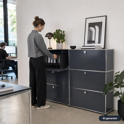 Anthrazitgraues USM Haller Highboard 2x3 mit sechs Klappen in einem modernen Büro mit Frau beim Einordnen von Unterlagen.