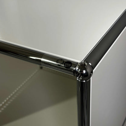 Nahaufnahme der Ecke eines weißen USM Haller Highboard 2x3 offen mit Chromverbindung und USM Markenlabel