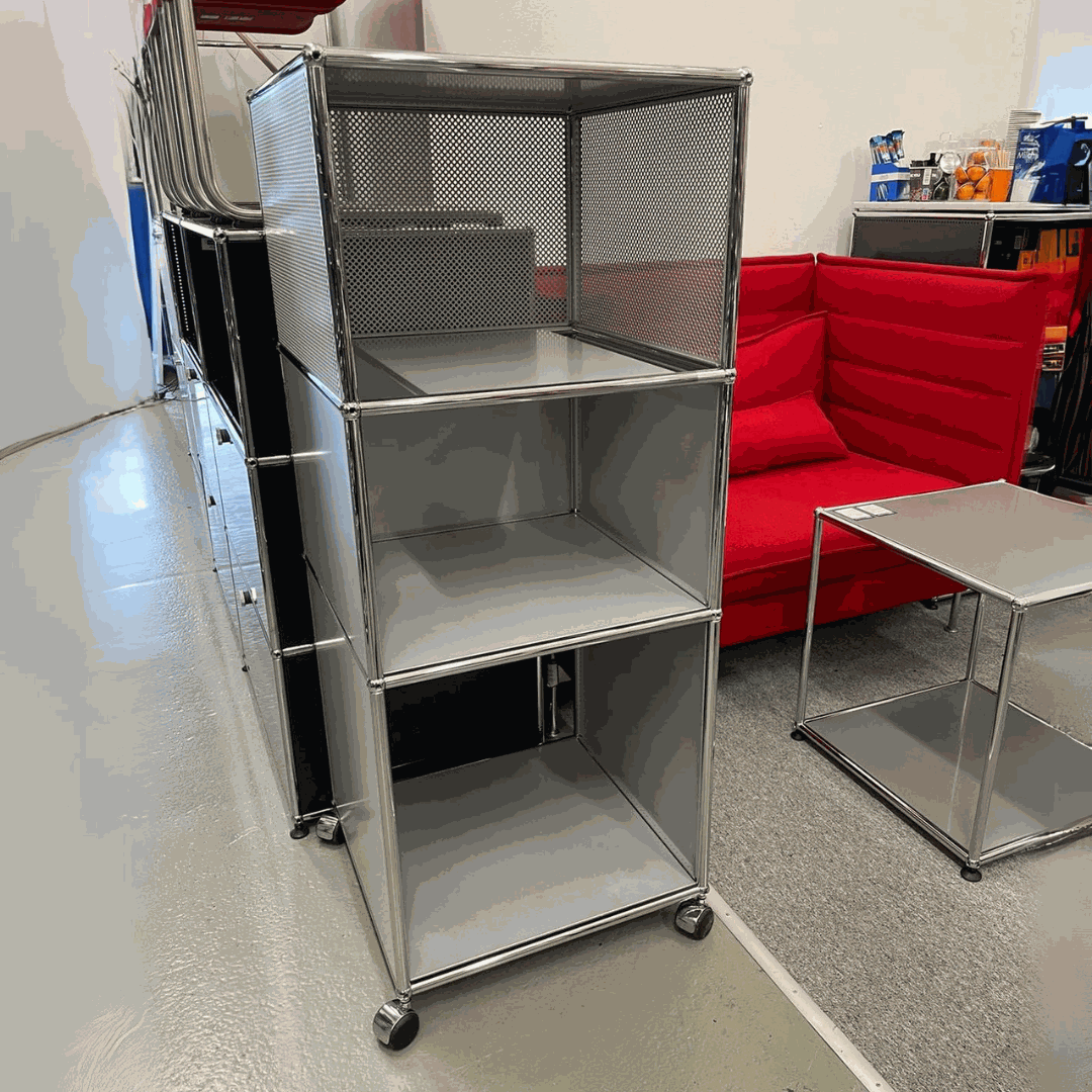 USM Haller highboard in matte silver with three compartments on wheels next to a red sofa and metal table