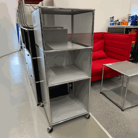 USM Haller highboard in matte silver with three compartments on wheels next to a red sofa and metal table