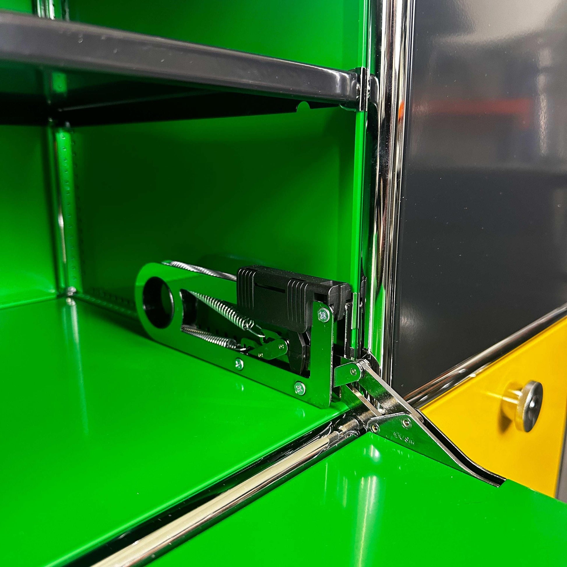 USM Haller Highboard mit grüner Klappe und gelben Schubladen, moderne Metallstruktur und Klappmechanismus