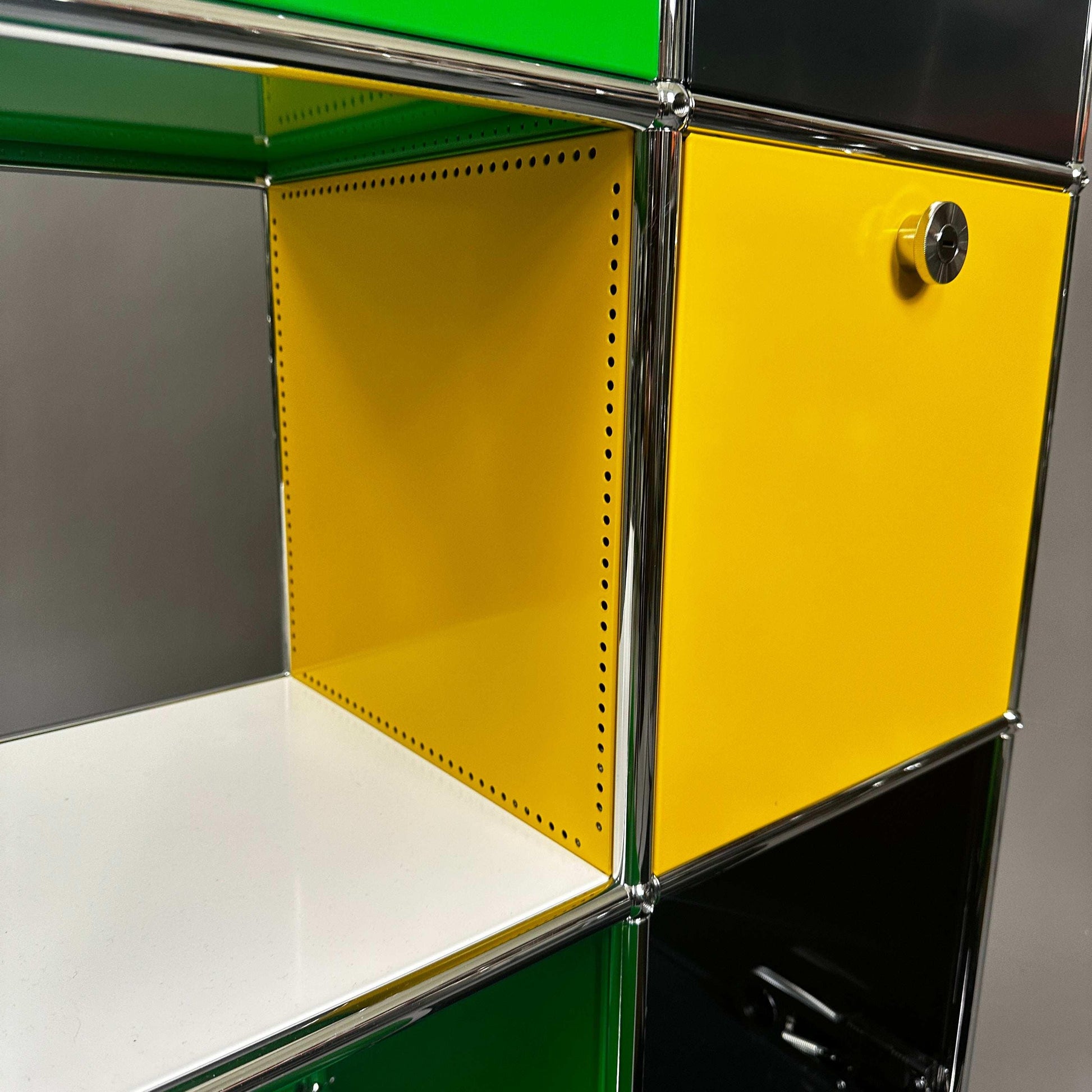 USM Haller Highboard Detailaufnahme gelbe Klappe mit grünem, schwarzem und weißen Fachrahmen