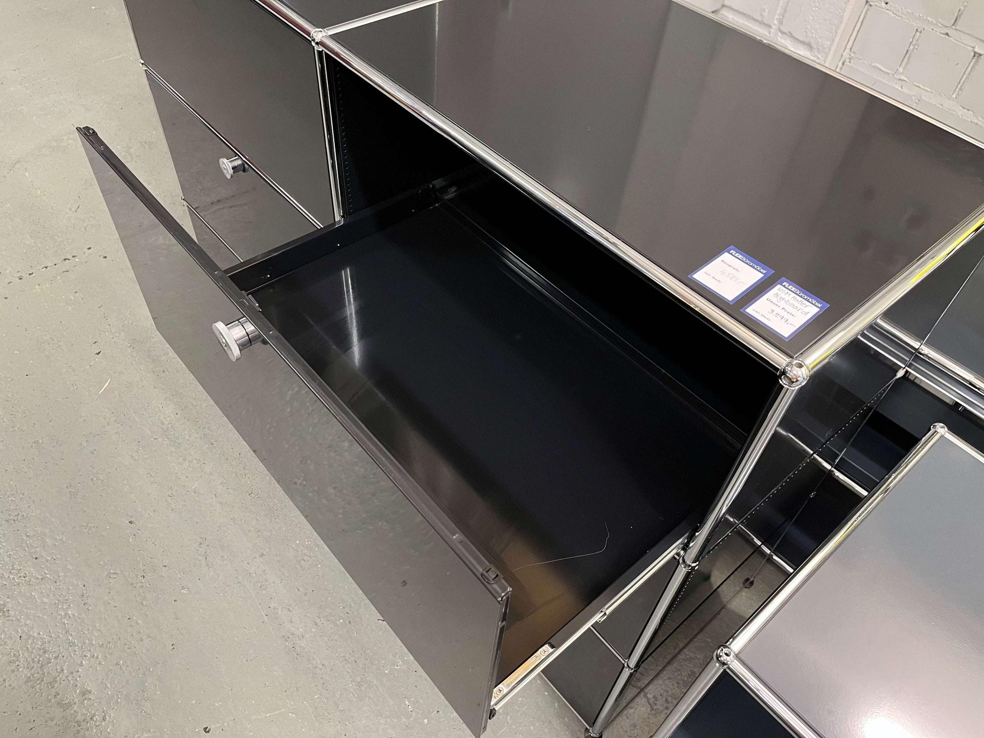 USM Haller Highboard in graphite black with open drawer and metal frame detailing