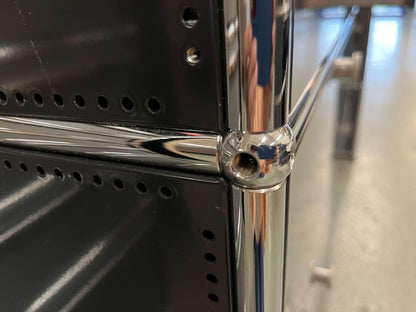 Close-up of black USM Haller Highboard corner with chrome metal connectors and perforated steel panels.