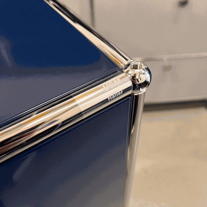 Close-up of USM Haller highboard corner in steel blue with chrome frame detailing and logo engraving