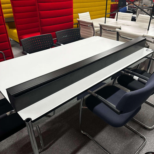 USM Haller Kabelkanal cable management system mounted on the side of a white office table with modern chairs around.