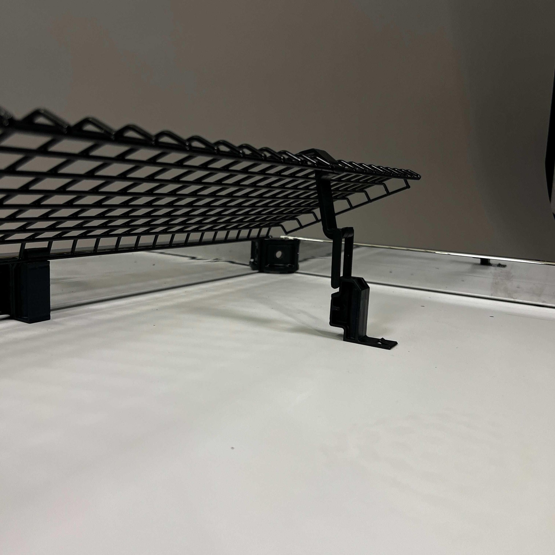 Black foldable USM Haller cable basket mounted under a desk for cable management with included fastening accessories