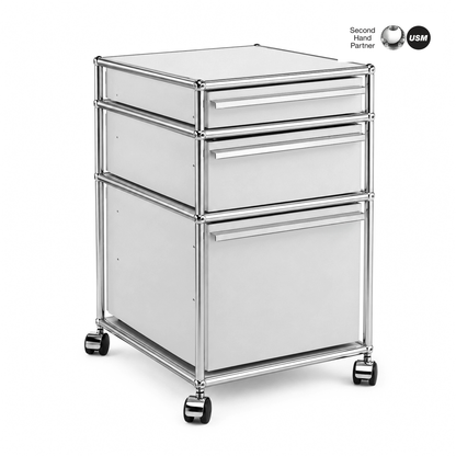 USM Haller Rollcontainer mit 3 lichtgrauen Schubladen, Chromgestell und Rollen.