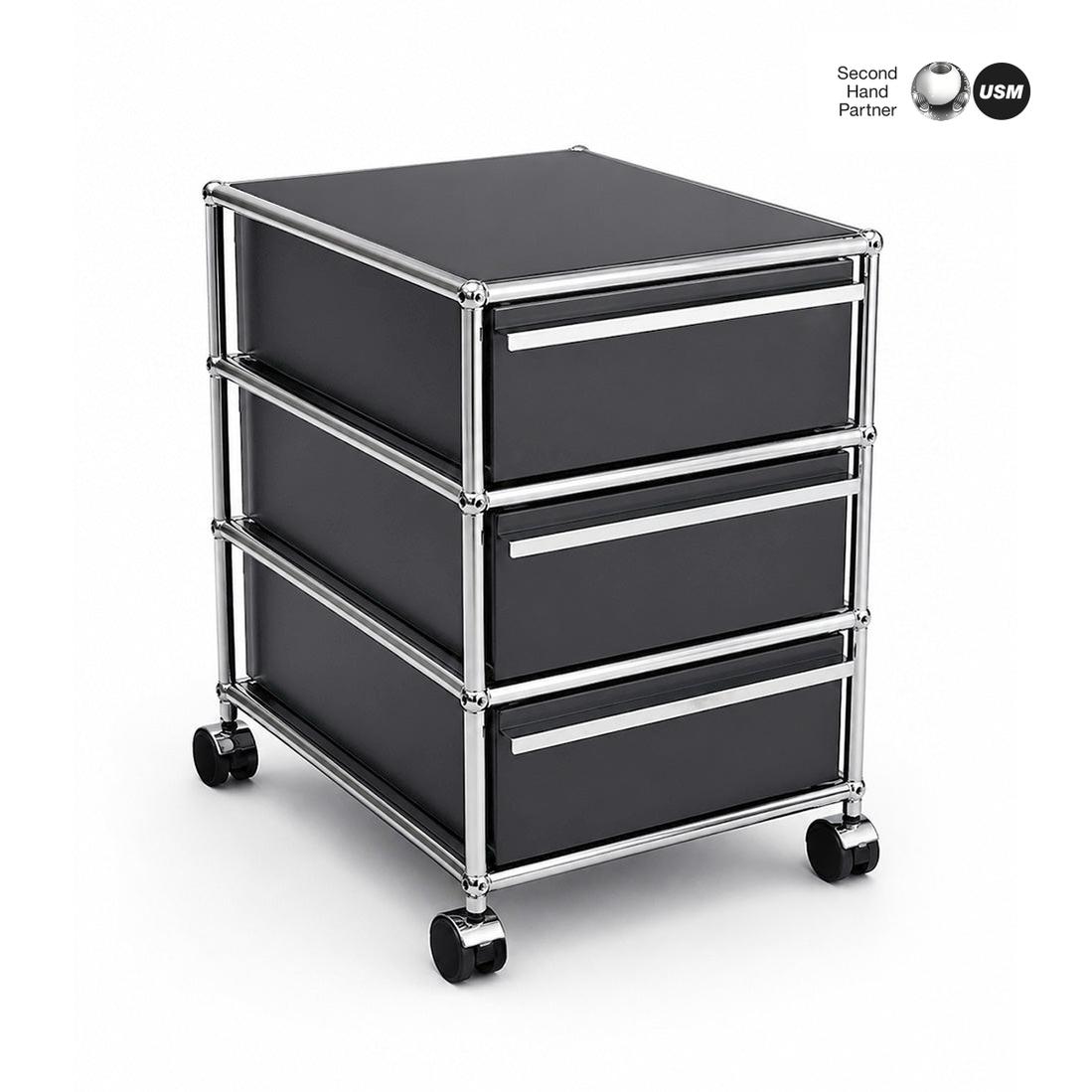 USM Haller Rollcontainer anthrazit mit 3 Schubladen, Chromgestell und Rollen.