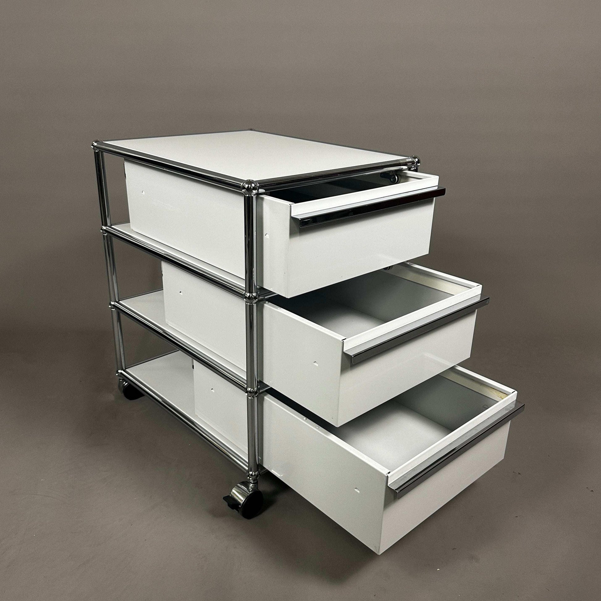 USM Haller light grey rollcontainer with three open drawers and chrome frame on wheels