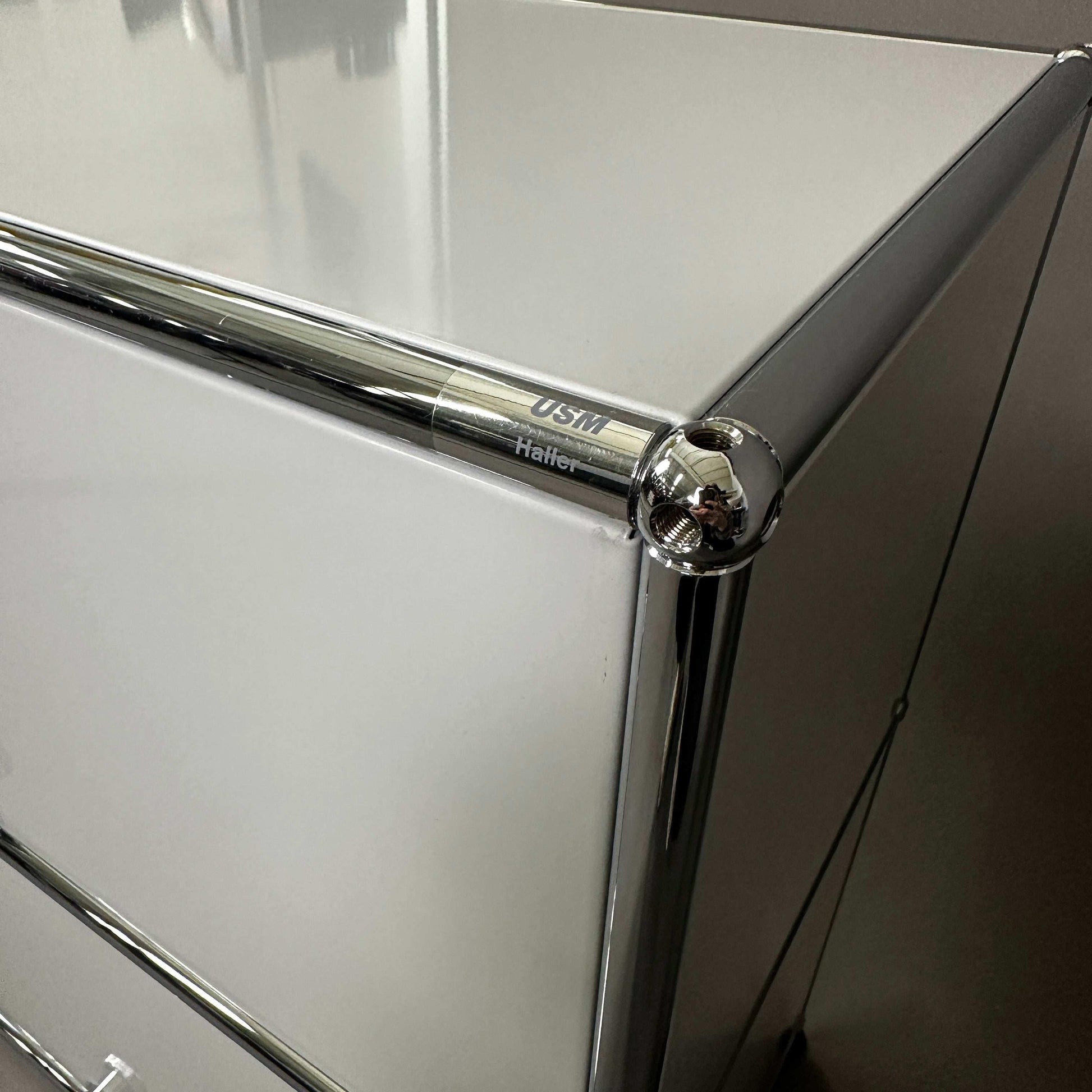 USM Haller light grey sideboard corner with chrome frame and logo close-up