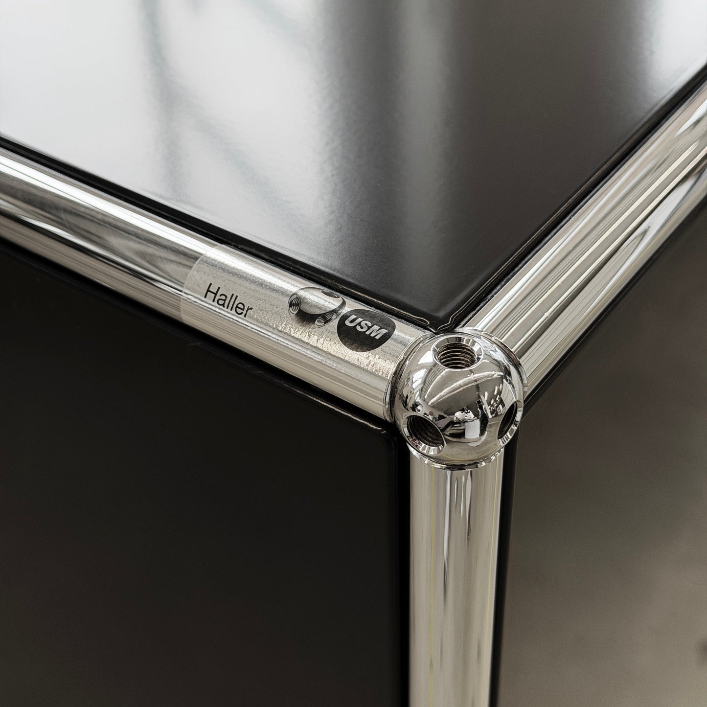 USM Haller Sideboard 2x2 in Schwarz mit glänzender Oberfläche und verchromten Eckverbindern.