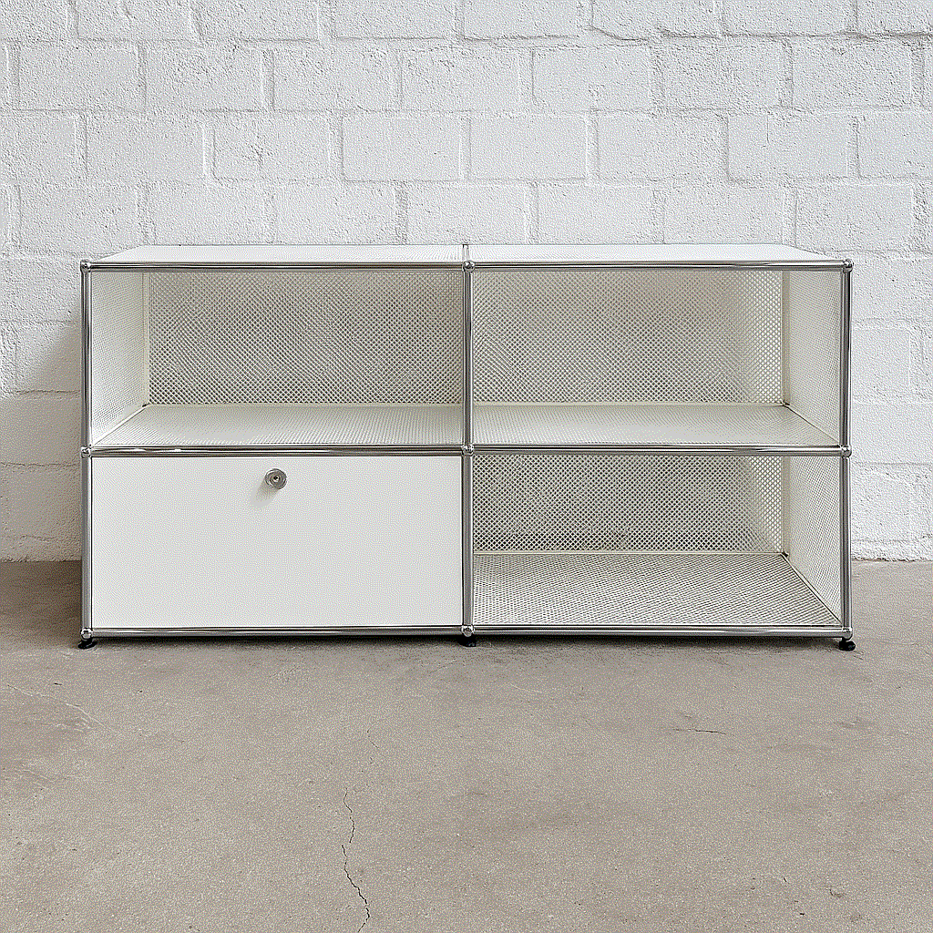 USM Haller Sideboard 2x2 weiß mit einer abschließbaren Klappe und perforierten Tablare vor weißer Ziegelwand