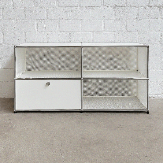 USM Haller Sideboard 2x2 weiß mit einer abschließbaren Klappe und perforierten Tablare vor weißer Ziegelwand