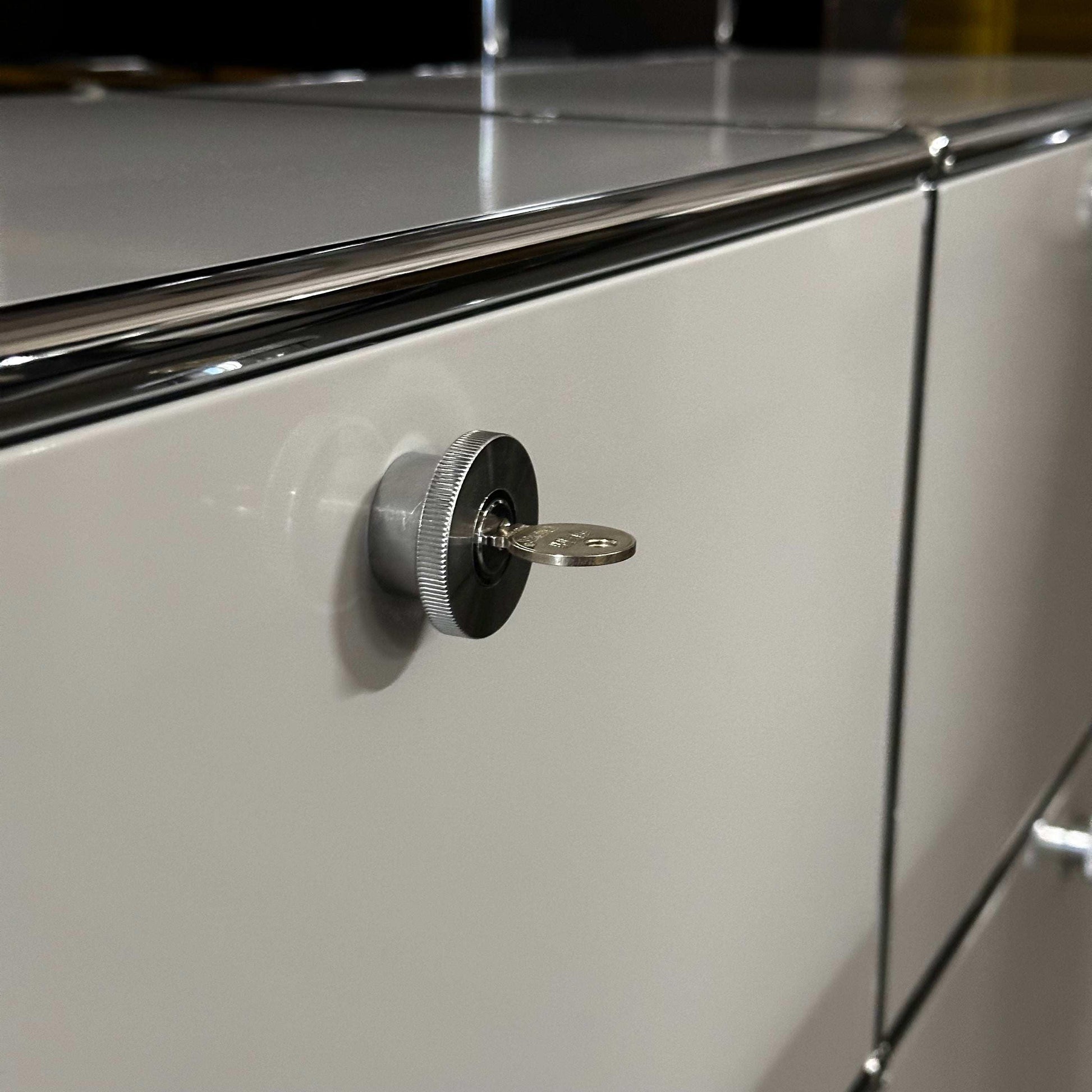 Close-up of light grey USM Haller Sideboard with locking key and chrome accents