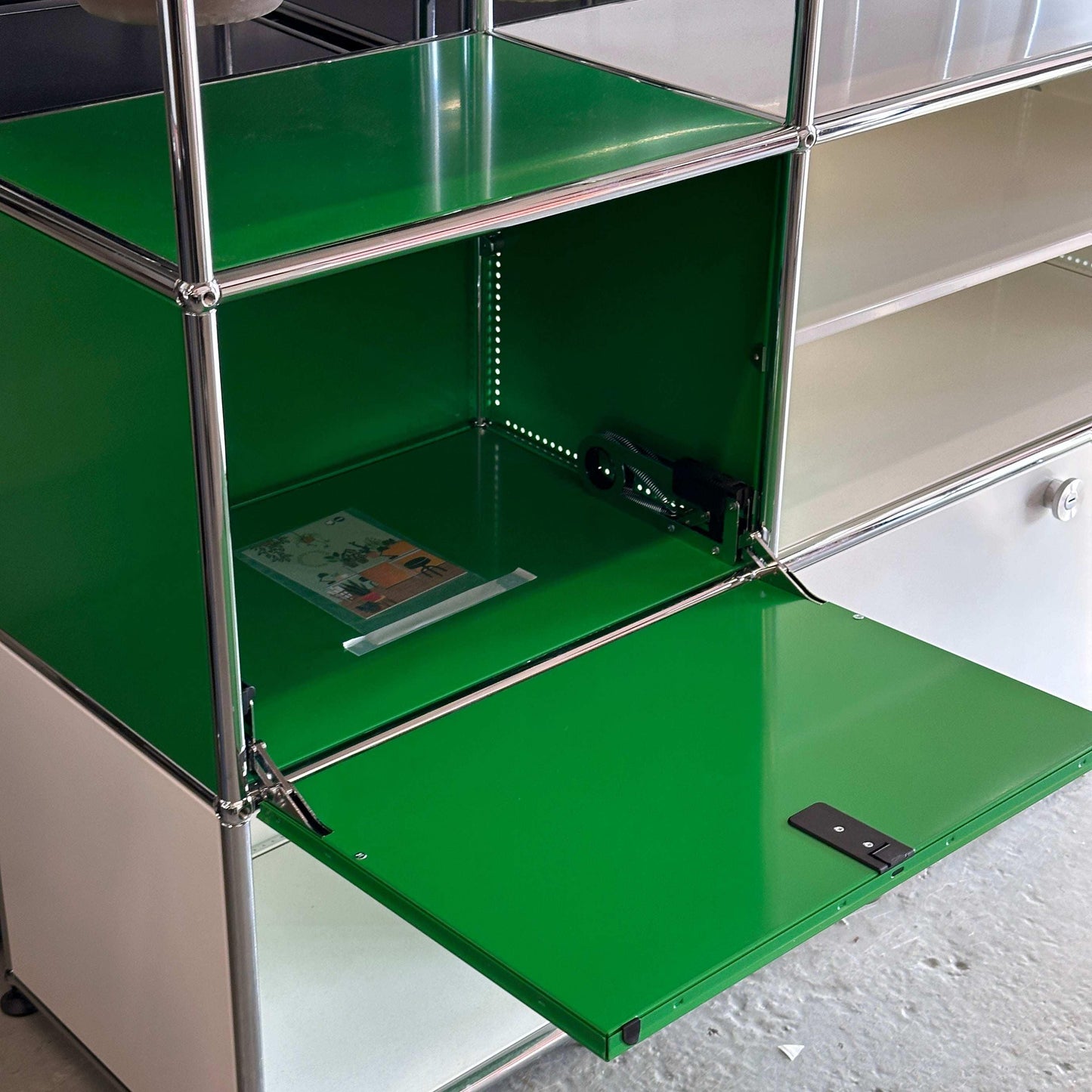 USM Haller Sideboard 3x3 in weiß und grün mit geöffnetem Fach und Pflanzeinsätzen
