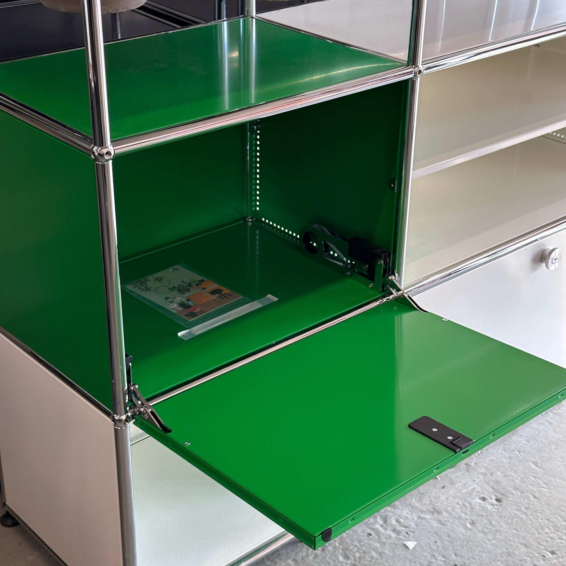 USM Haller Sideboard 3x3 in weiß und grün mit geöffnetem Fach und Pflanzeinsätzen