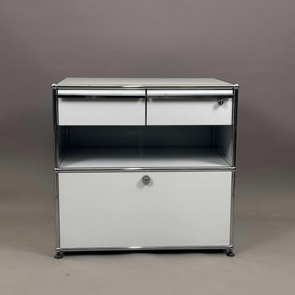 USM Haller Sideboard lichtgrau mit zwei Schubladen und abschließbarem Auszug auf grauem Hintergrund