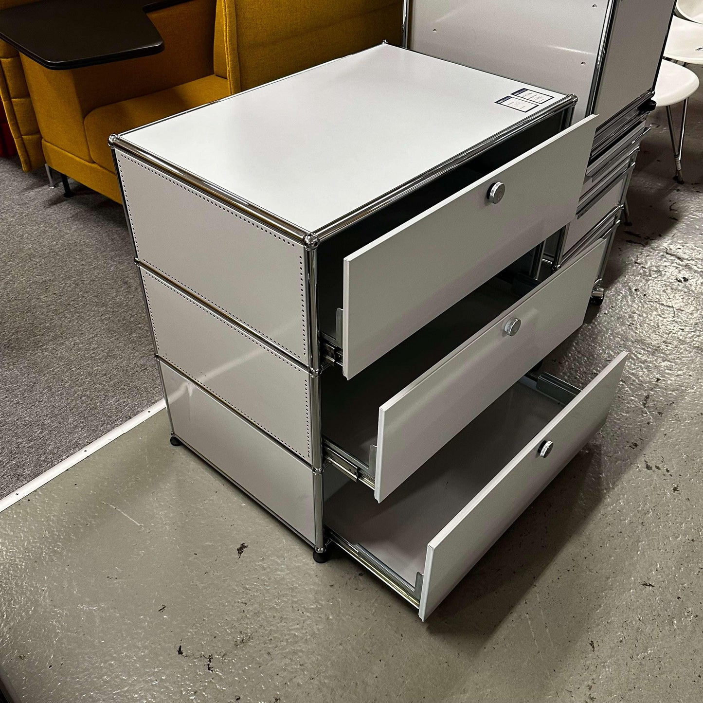 USM Haller light gray sideboard with three open drawers and metal frame.