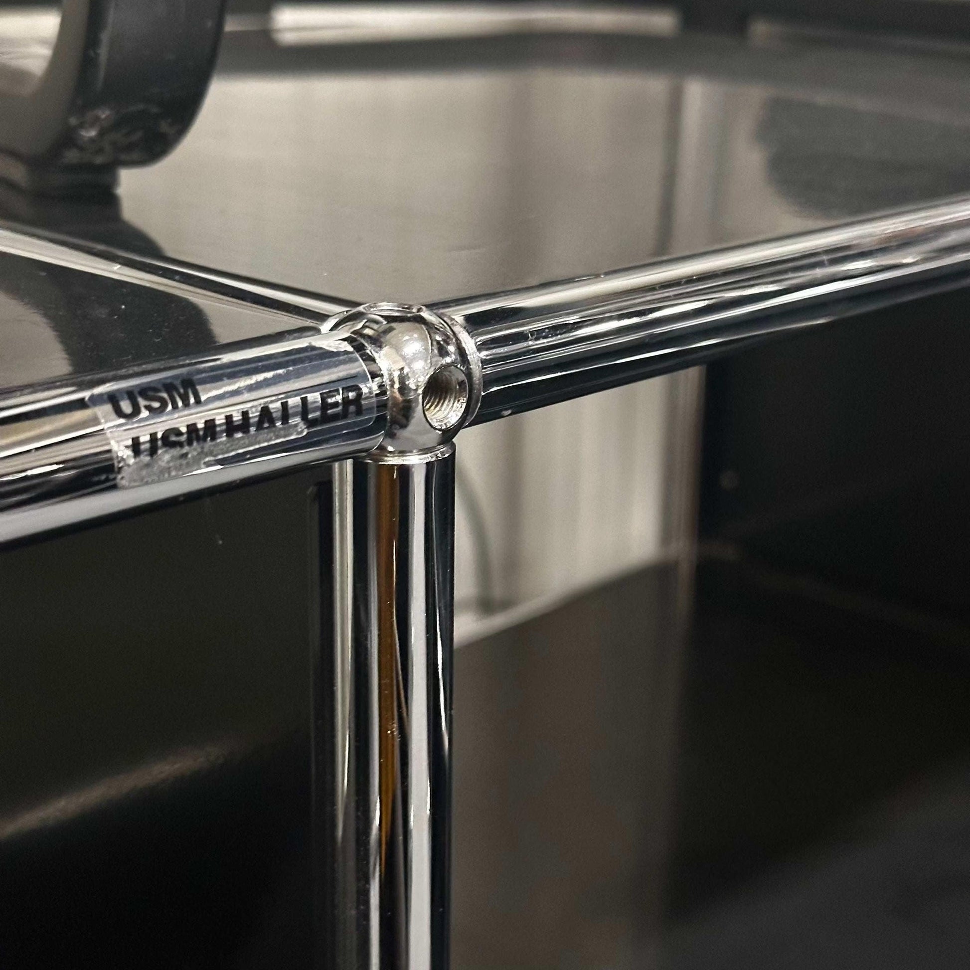 Close-up of the chrome joint detail on a black USM Haller Sideboard with 2x2 open compartments, measuring 152x74x52 cm